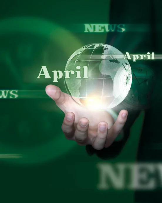 Hand hält kugelförmige Welt mit "April" und "News"-Texten, symbolisiert globale Nachrichten im April.