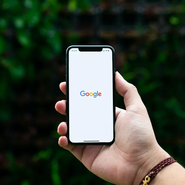 Das Bild zeigt ein Smartphone, auf dem der Startbildschirm von Google zu sehen ist. Im Hintergrund ist eine grüne, unscharfe Kulisse zu erkennen. Diese Darstellung eignet sich hervorragend, um die digitale Kompetenz und technologische Expertise einer IT-A