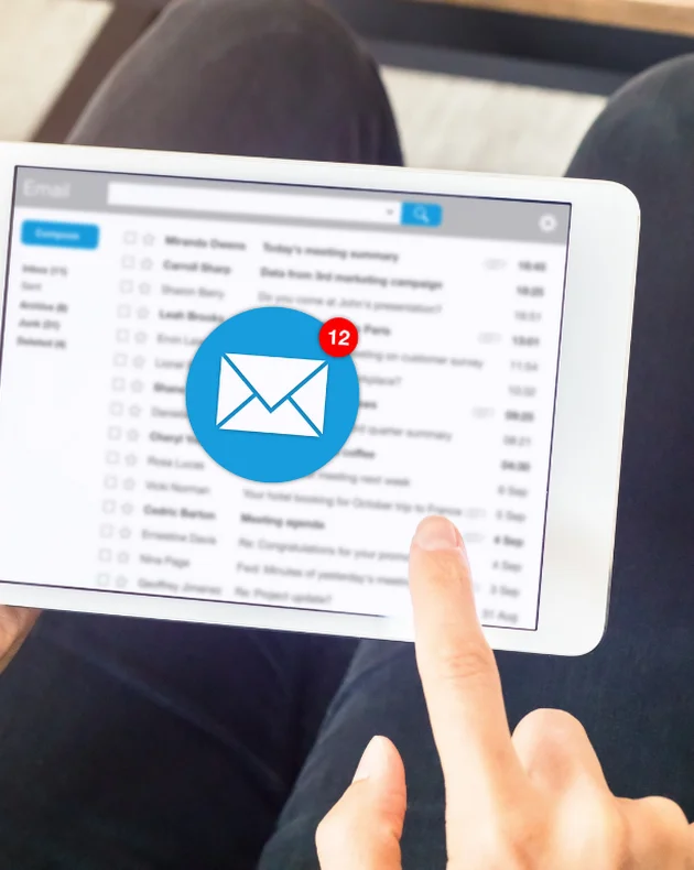 Person hält Tablet mit geöffnetem E-Mail-Posteingang, zeigt auf Nachricht mit Benachrichtigungssymbol für zwölf ungelesene Mails.
