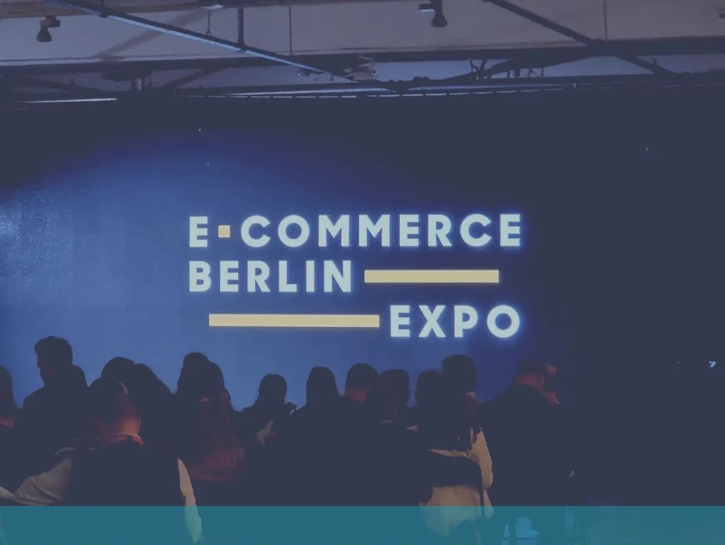 Personengruppe bei einer Veranstaltung mit blauem Hintergrund, Aufschrift "E-Commerce Berlin Expo".