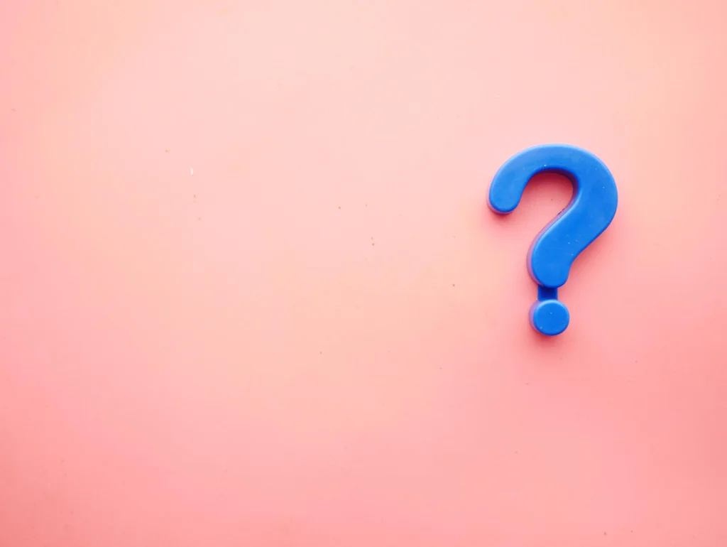 Blaues Fragezeichen auf rosa Hintergrund, symbolisiert Unklarheit oder Fragen.