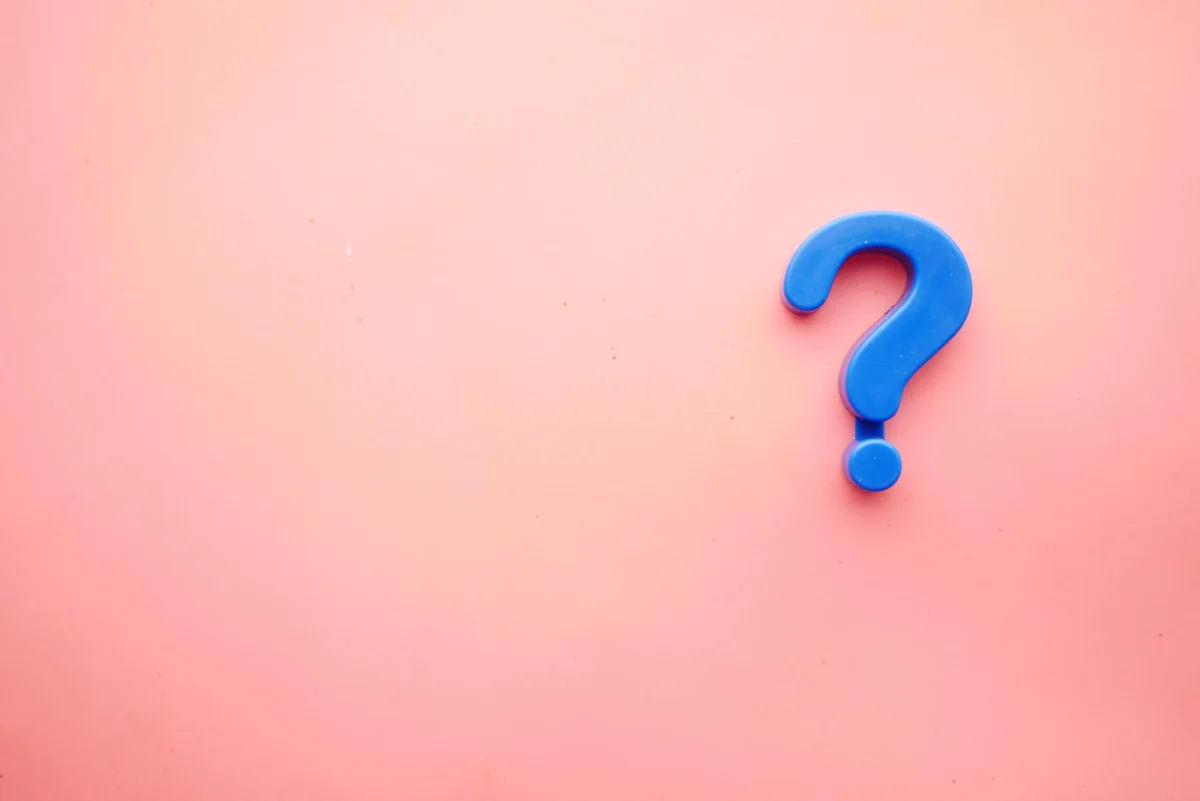 Blaues Fragezeichen auf rosa Hintergrund, symbolisiert Unklarheit oder Fragen.