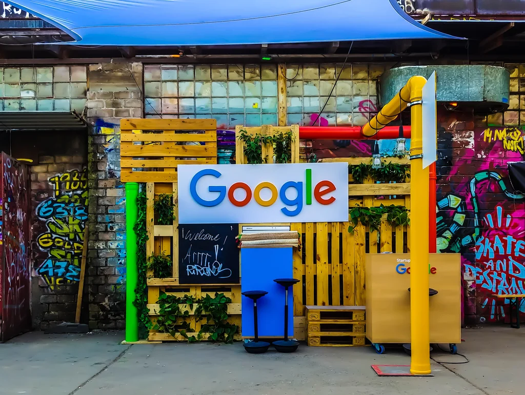 Bunter Google-Stand aus Paletten mit Graffiti-Hintergrund und Pflanzen, dekorativ und kreativ gestaltet.