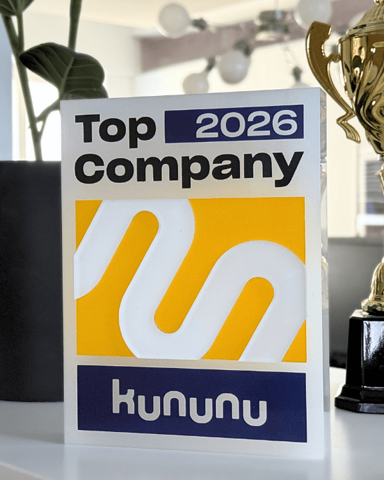 Kununu-Auszeichnung "Top Company 2026", umgeben von einer Pflanze und einem Pokal, auf einem weißen Regal.
