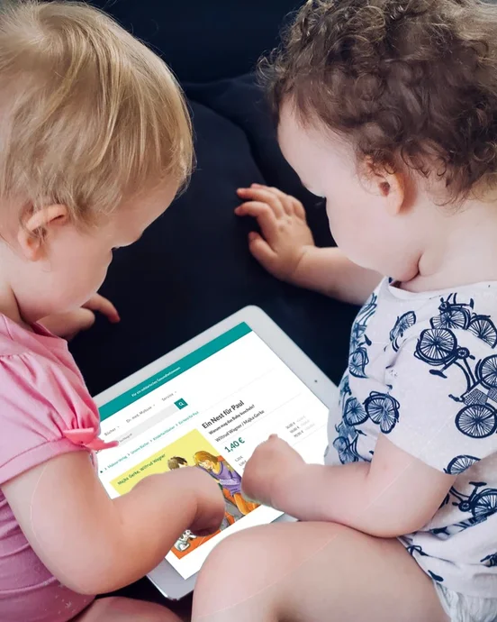 Zwei Kleinkinder interagieren mit einem Tablet auf einem Sofa.