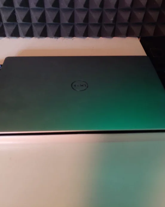 Geschlossener Laptop auf weißem Tisch, Hintergrund mit schallabsorbierenden Schaumstoffplatten in einem abgedunkelten Raum.