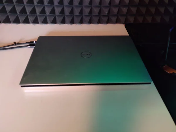 Geschlossener Laptop auf weißem Tisch, Hintergrund mit schallabsorbierenden Schaumstoffplatten in einem abgedunkelten Raum.