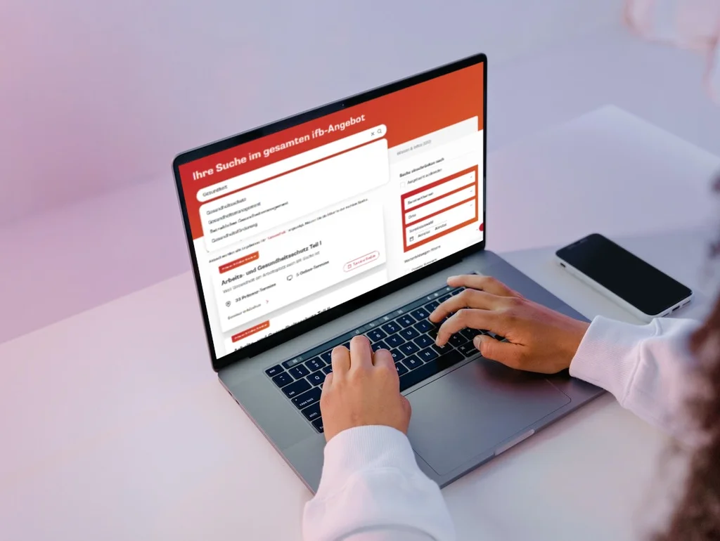 Person nutzt Laptop mit geöffneter Webseite zur Unternehmenssuche vor neutralem Hintergrund.