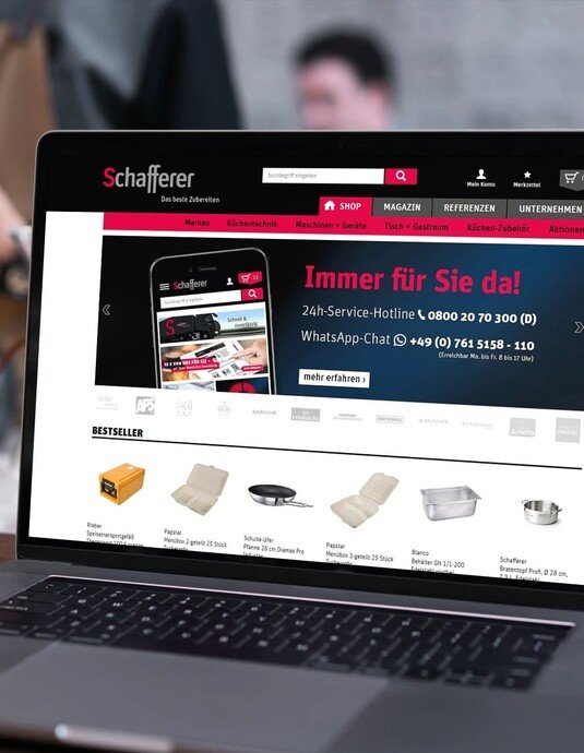 Laptop auf einem Tisch, zeigt eine geöffnete Webseite mit Einkaufsoptionen für Möbel und Kontaktdetails im Vordergrund.