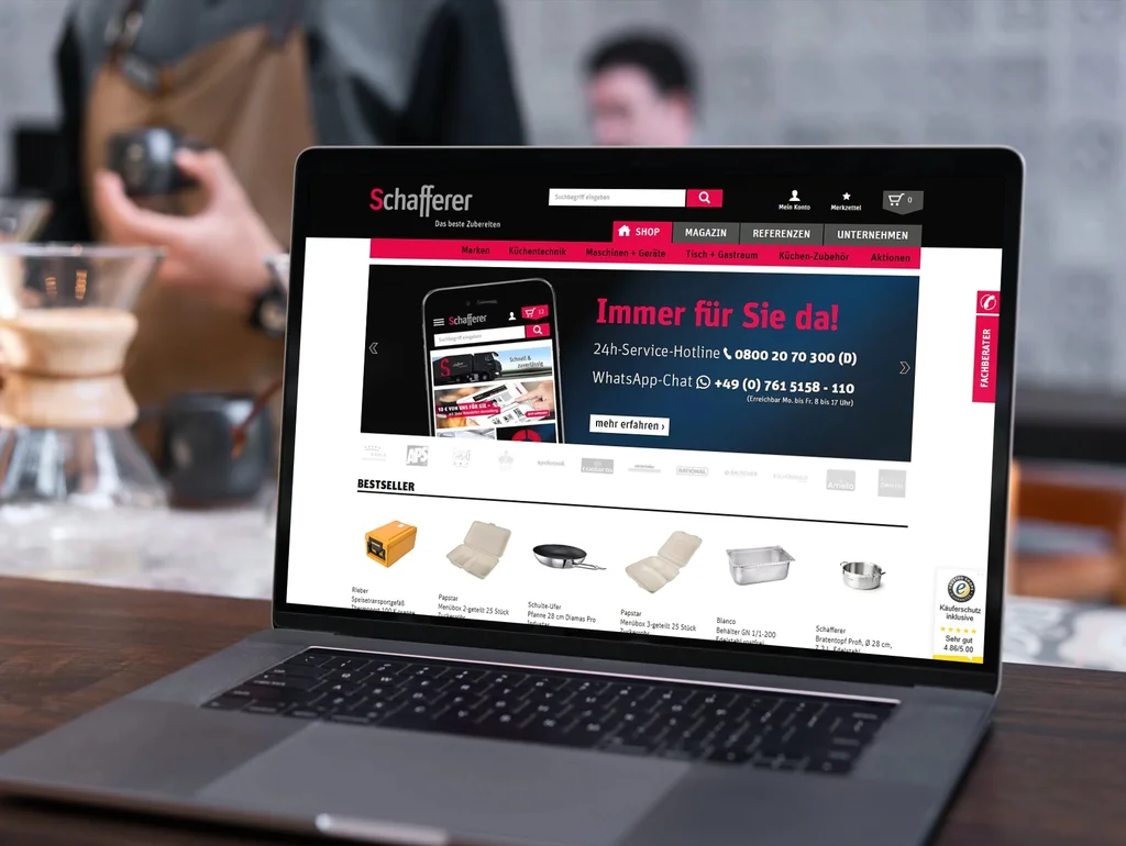 Laptop auf einem Tisch, zeigt eine geöffnete Webseite mit Einkaufsoptionen für Möbel und Kontaktdetails im Vordergrund.