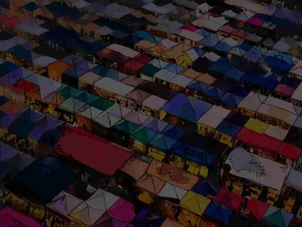 Luftaufnahme eines Marktplatzes mit dicht aneinandergereihten, bunten Zeltdächern in verschiedenen Farben und Mustern.