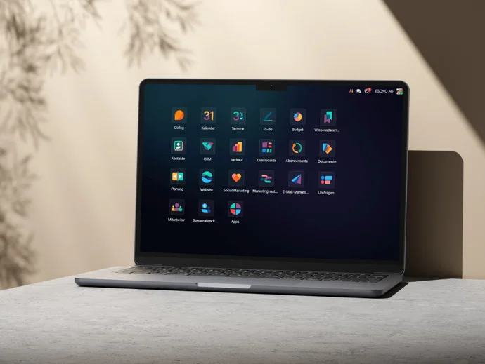 Laptop auf Tisch mit geöffnetem Display, zeigt Symbole einer Desktop-Oberfläche unter neutralem Licht.