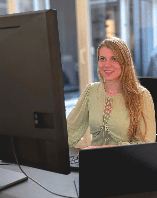 Eine Person arbeitet an einem Schreibtisch mit Computer in einem modernen Büro.