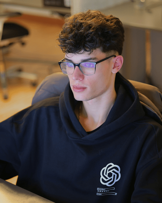 Eine Person mit Brille arbeitet konzentriert an einem Computerbildschirm in einem modernen Büro.