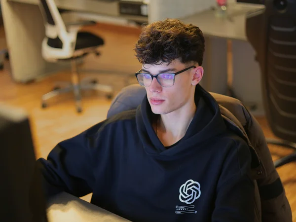 Eine Person mit Brille arbeitet konzentriert an einem Computerbildschirm in einem modernen Büro.